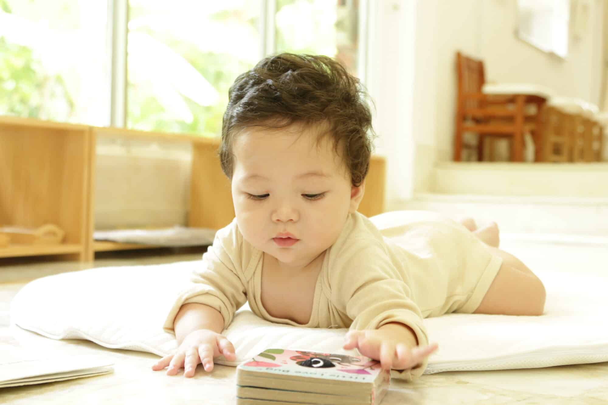 A baby lying on the floor reading a children's book