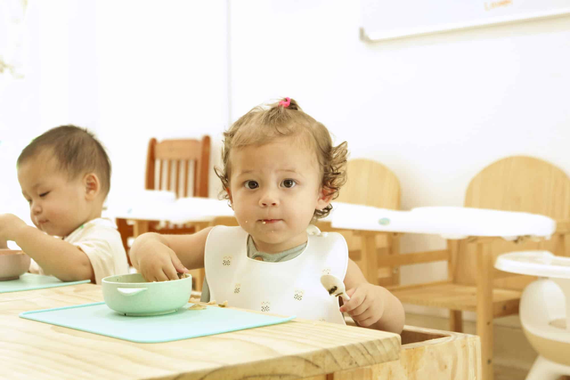 An infant eating a healthy meal in a montessori pre-school
